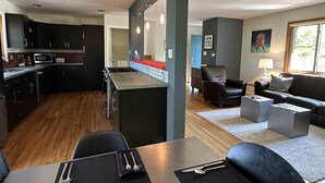 Une cuisine moderne avec des meubles de couleur sombre, un îlot central et un coin repas avec une table dressée pour deux personnes.