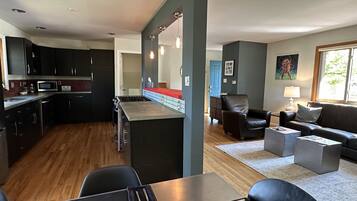 A modern kitchen with dark cabinets, a central island, and a dining area with a table set for two.