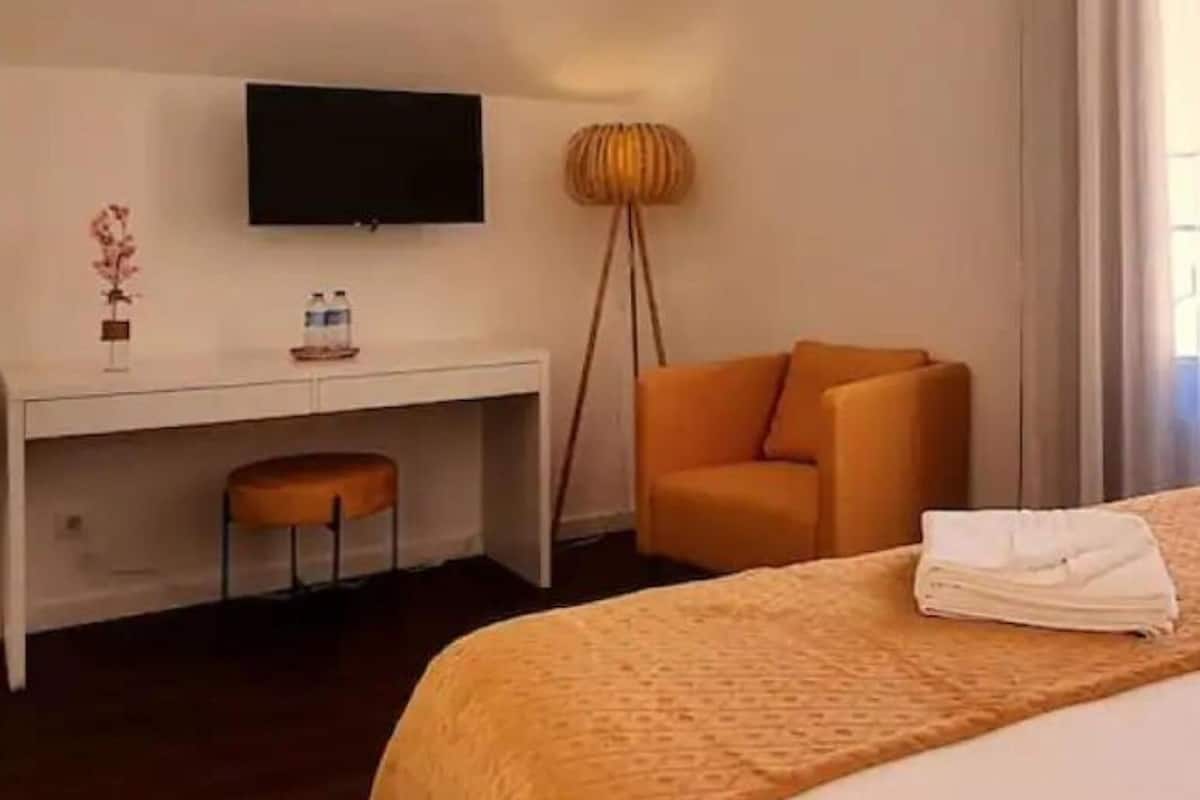 A hotel room with a bed, a desk, a chair, a television, and a window with curtains.