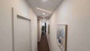 Een moderne hal met een houten vloer, witte wanden en inbouwverlichting.