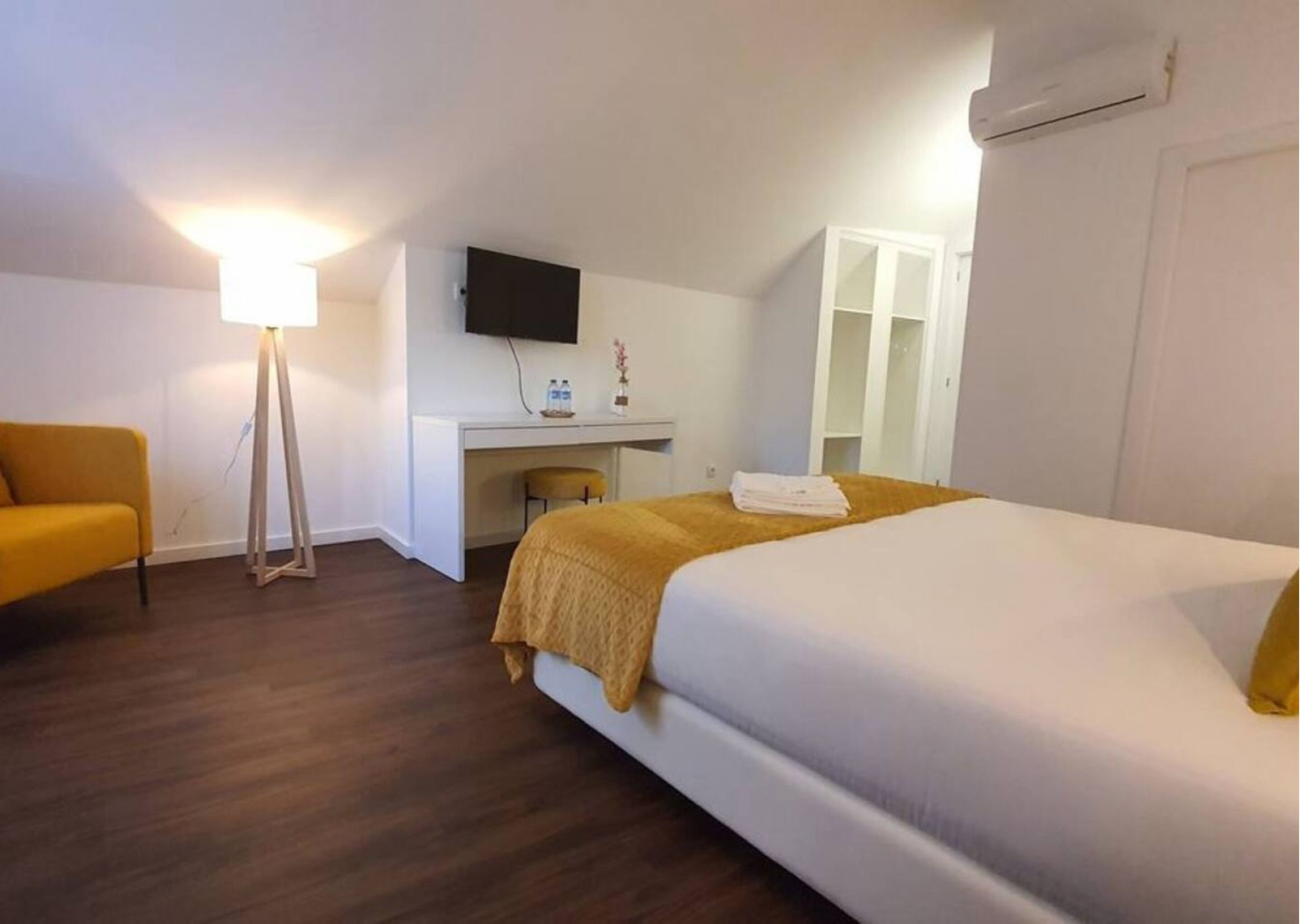 Habitación de hotel con cama, escritorio, silla, sofá y lámpara de pie.