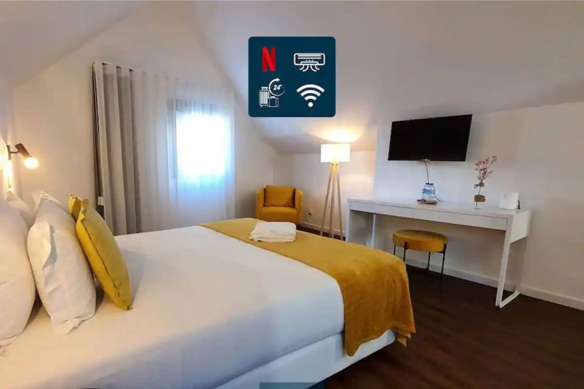 A hotel room with a bed, a desk, a chair, a TV, and a sign indicating amenities like Wi-Fi and a 24-hour service.