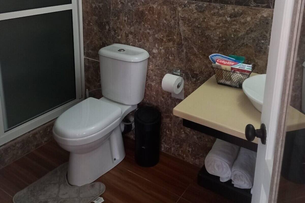 Um banheiro pequeno com vaso sanitário, chuveiro e pia.