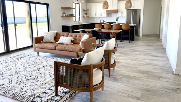 A modern living room with a brown leather sofa, a patterned rug, and wicker chairs. - Modern Getaway with Community Pool near Golf, Boating & Gorge Concerts! (Mattawa)