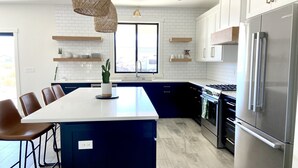 A modern kitchen with a central island, stainless steel appliances, and a large window. - Modern Getaway with Community Pool near Golf, Boating & Gorge Concerts! (Mattawa)