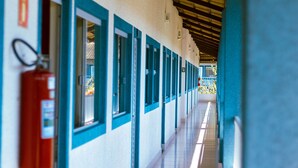 A corridor with doors and windows, a fire extinguisher, and a tiled floor.