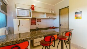 A kitchen with a microwave, refrigerator, and red bar stools.