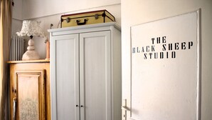 Een kamer met een witte kast, een lamp op een houten plank en een muur met de tekst 'The Black Sheep Studio'.