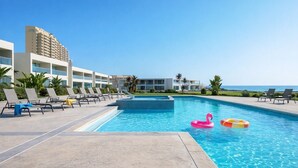 A pool area with lounge chairs and a swimming pool. - 6th-Floor Oceanfront Condo - Indoor Pools, Sauna, Private Beach (Rosarito BC)