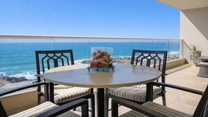 A round table with two chairs on a balcony overlooking the ocean. - 6th-Floor Oceanfront Condo - Indoor Pools, Sauna, Private Beach (Rosarito BC)