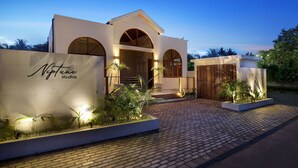 A modern building with a sign reading "Neptune Studios" and a brick pathway leading to the entrance. - Neptune Studios Lombok (Kuta)