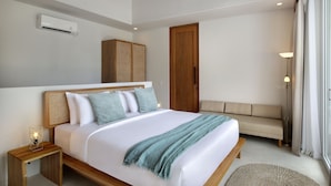 A modern bedroom with a large bed, wooden headboard, and a wooden wardrobe. - Neptune Studios Lombok (Kuta)
