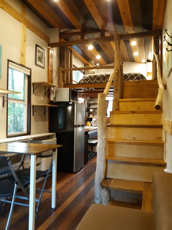 A rustic interior with a wooden staircase, a kitchen area, and a dining space.