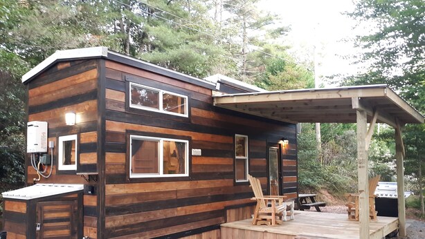 A cabin with a deck, a grill, and a water heater. - Big Porch Tiny House (Brevard)