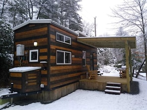 A cabin with a wooden exterior, a covered porch, and a small outdoor seating area.