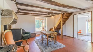 A spacious living area with a wooden staircase, a dining table, and a sofa. - Thélème - Pouilloux - Gîte (POUILLOUX)