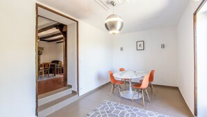 A modern dining area with a round table, orange chairs, and a marble-patterned floor. - Thélème - Pouilloux - Gîte (POUILLOUX)