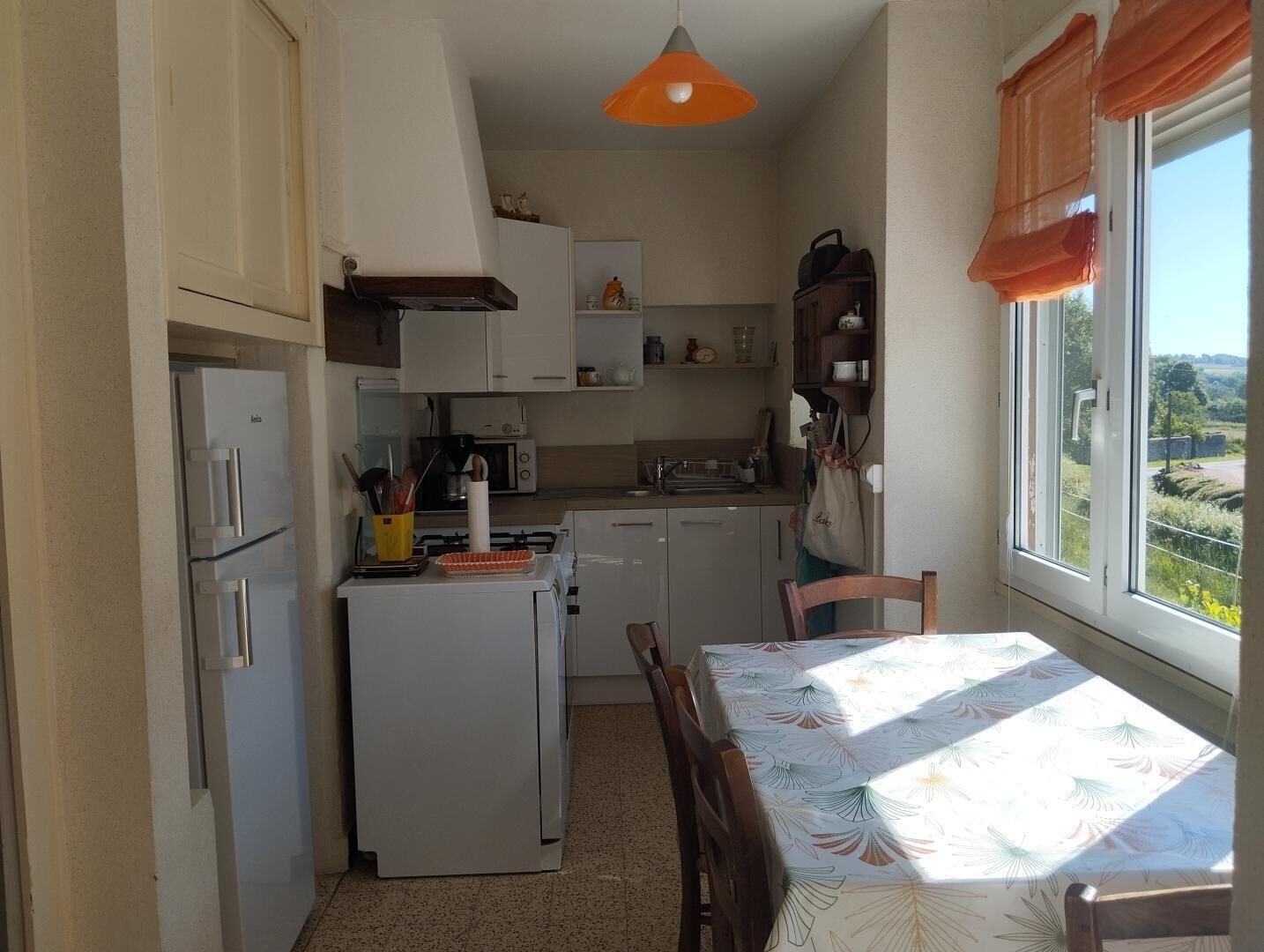 Cozinha compacta com geladeira, fogão, micro-ondas e mesa de jantar com cadeiras.