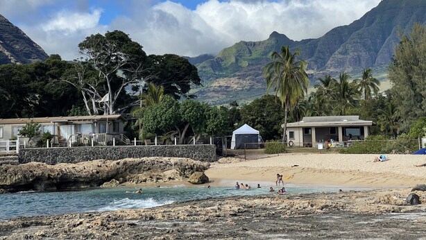 A beach with a pool, palm trees, and mountains in the background. - New 4br home 5 min from the beach-Paradise escape (Waianae)