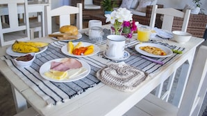 Ein Esstisch mit Tellern voller Essen, einer Tasse, einem Glas Orangensaft und einer Vase mit Blumen.