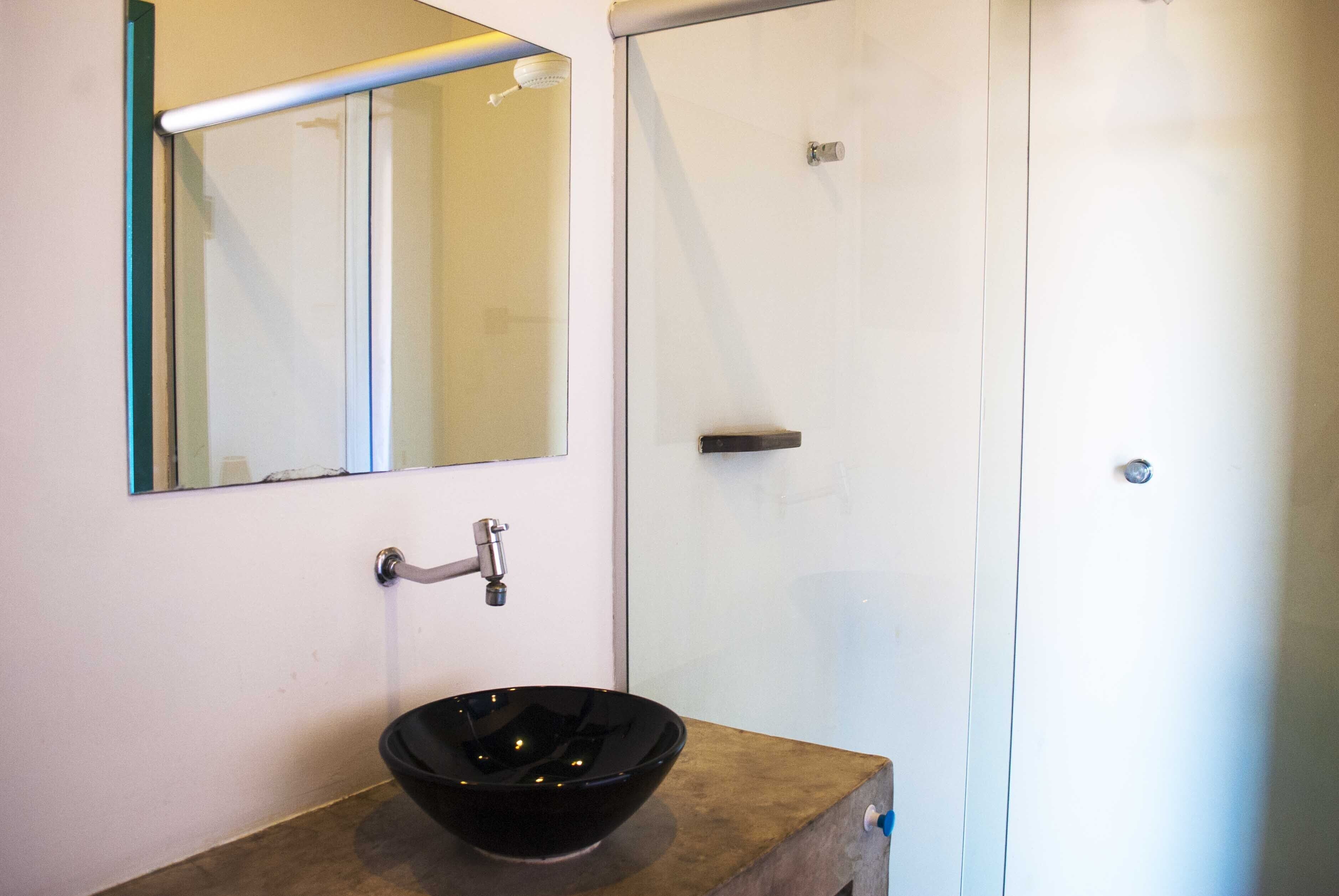 A bathroom with a black vessel sink, a mirror, and a shower door.