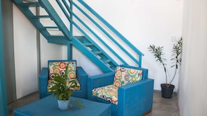 Eine blaue Treppe, eine blaue Sofagarnitur mit bunten Kissen und zwei Zimmerpflanzen.