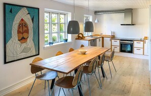 A modern kitchen with a wooden table and chairs, a large window, and a painting on the wall. - Beautiful home in Samsø with WiFi (Samsø)