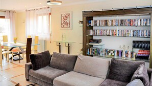 A living room with a grey sofa, a glass coffee table, a dining table with chairs, and a bookshelf filled with books. - 3 bedroom stunning apartment in Autun (Autun)