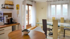 A modern kitchen with a coffee machine, a toaster, and a small plant. There is a glass dining table with chairs and a view of the outside through large windows. - 3 bedroom stunning apartment in Autun (Autun)