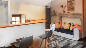 A modern living room with a sofa, a dining area with a wooden table, and a fireplace. - 3 bedroom stunning apartment in Autun (Autun)