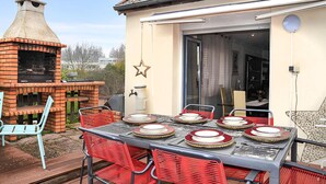 An outdoor dining area with a brick grill, red chairs, and a table set for four. - 3 bedroom stunning apartment in Autun (Autun)