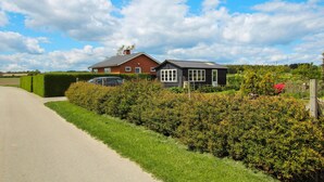 A rural property with a paved driveway, a red brick house, and a black shed.