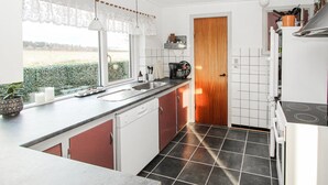 A compact kitchen with a dishwasher, a coffee machine, and a stove.
