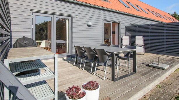 A patio with a table and chairs, a grill, and potted plants. - 2 bedroom beautiful apartment in Samsø (Samsø)