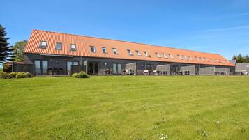 A modern building with a red-tiled roof, large windows, and a spacious lawn area.