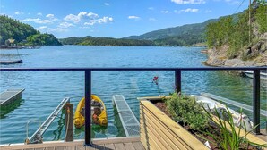 A lakeside dock with a wooden deck, a yellow boat, and a white boat.