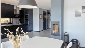 A modern kitchen with dark cabinetry, a large pendant light, and a dining area with a white table.