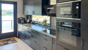 A modern kitchen with a large island, stainless steel appliances, and a view of a lake.