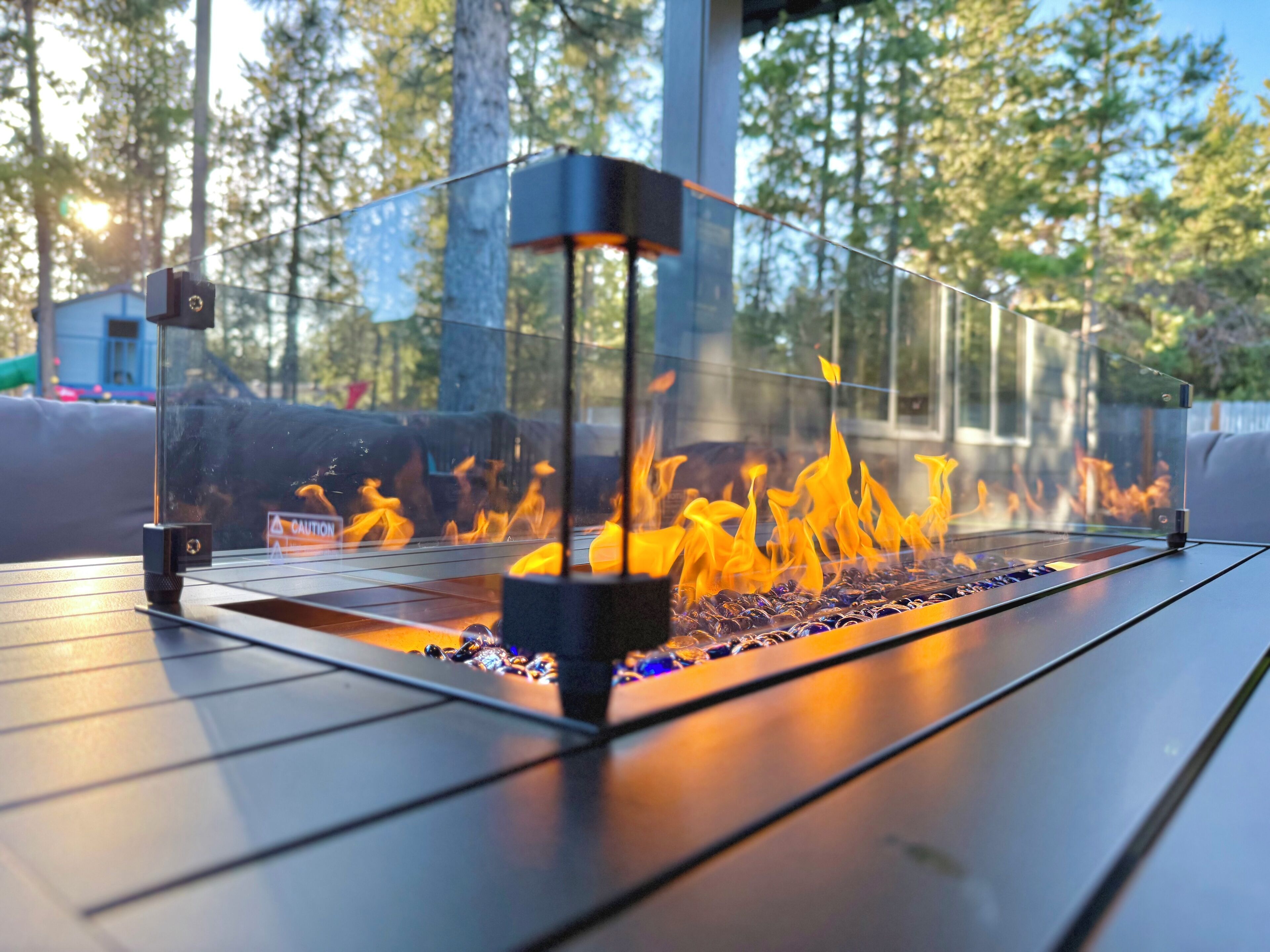 A glass-enclosed fire feature with a metal grate, surrounded by a clear glass enclosure.