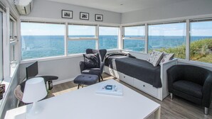 A room with a large window overlooking the sea, a bed, a desk, and a chair. - Beautiful apartment in Samsø (Samsø)