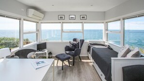 A compact room with a bed, a desk, and a chair, all facing a large window overlooking the sea. - Beautiful apartment in Samsø (Samsø)