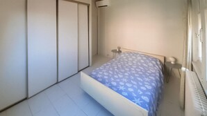 A small, clean room with a bed, a radiator, and a window. - 2 bedroom beach front home in Cagnes-sur-mer (Cagnes-sur-mer)