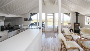 Un amplio espacio de estar con una isla grande, muebles blancos y vistas al exterior.