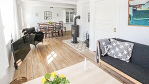 Un salon confortable avec un canapé, une table à manger et des chaises, une cheminée et un téléviseur.