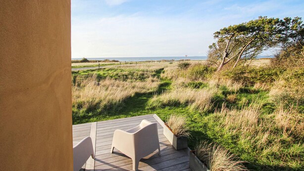 Eine Terrasse mit zwei Stühlen mit Blick auf eine Küstenlandschaft und Meer.