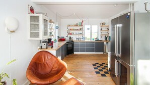 Eine moderne Küche mit Holzboden, einem großen Kühlschrank und einem Essbereich mit einem braunen Ledersessel.