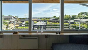 A room with a large window overlooking a residential area, a small table with chairs, and a radiator below the window. - Amazing home in Aabenraa (Aabenraa)