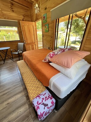 Una habitación de cabaña de madera con una cama, una silla y una mesita.