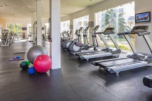 Uma academia com esteiras, bolas de exercício e aparelhos de musculação.