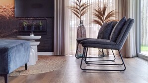 A modern dining area with a dark wood dining table, a blue upholstered chair, and a white pedestal sink. - Lovely home in Voorthuizen with WiFi (Voorthuizen)